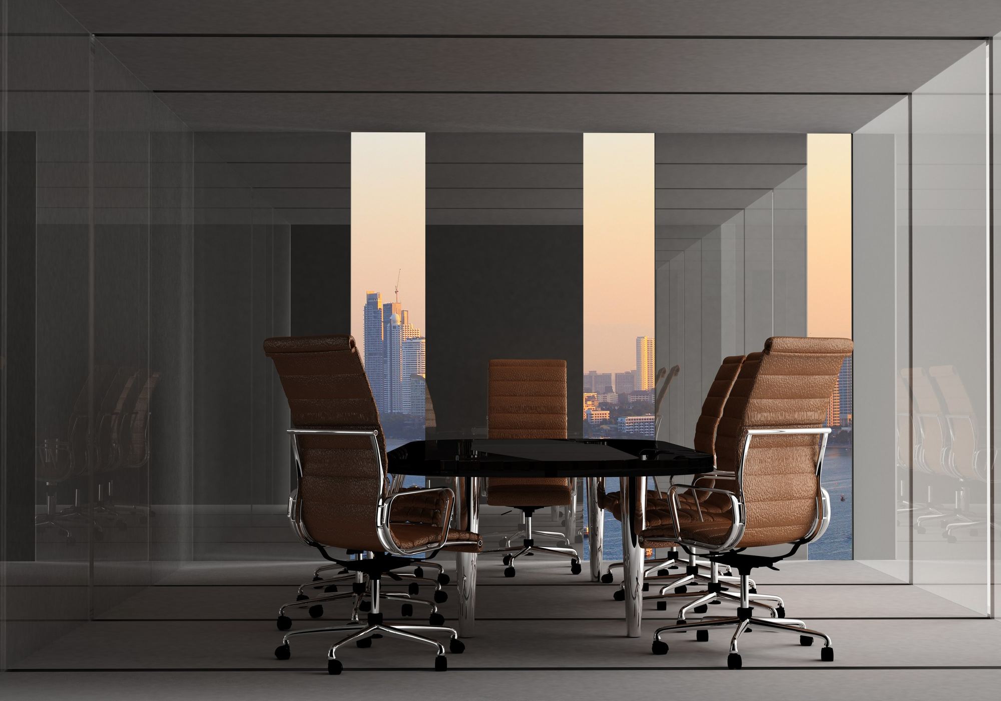 An empty glass-walled conference room overlooking a city at dusk